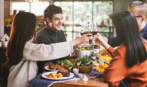 Friends toasting wineglasses while sitting at table in restaurant