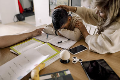 Mother sitting tired son at table in living room