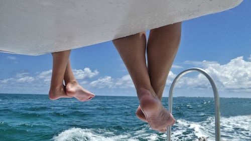 Low section of woman in sea against sky