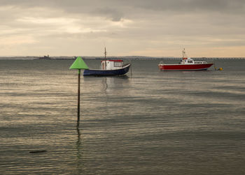 Boat moored in sea against sky during sunset