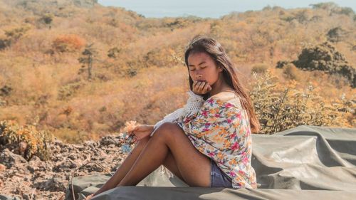 Side view of teenage girl with eyes closed sitting on land during summer