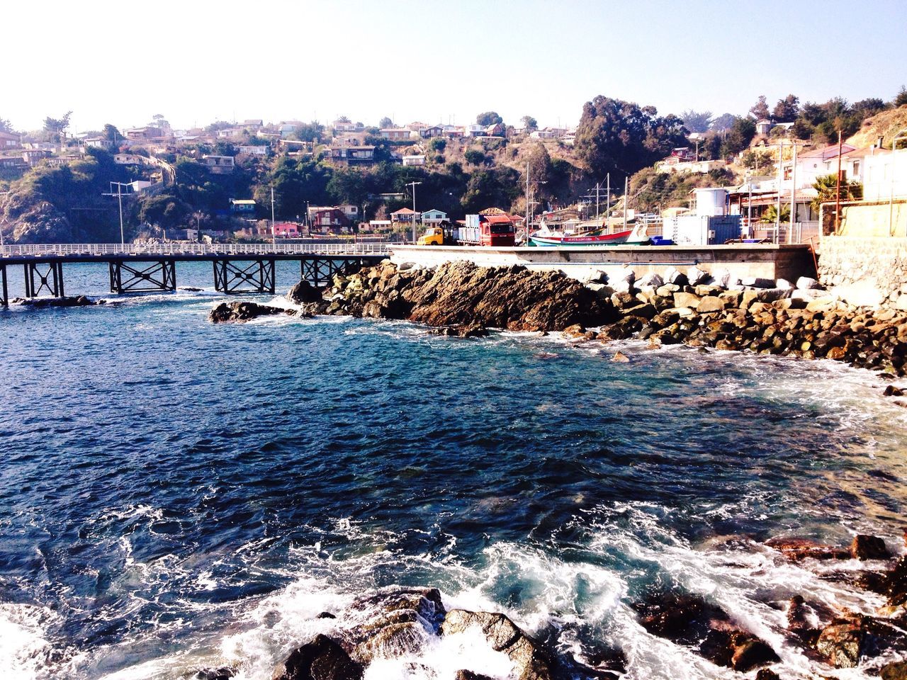 water, built structure, architecture, sea, building exterior, bridge - man made structure, clear sky, connection, river, city, wave, surf, mountain, incidental people, waterfront, beach, transportation, day, bridge, nature