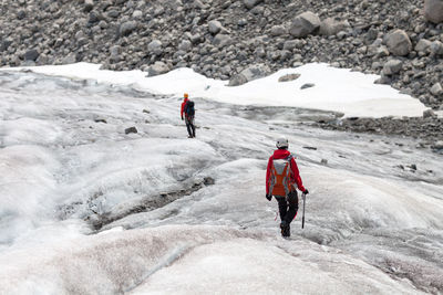 Rear view of people hiking on glacier