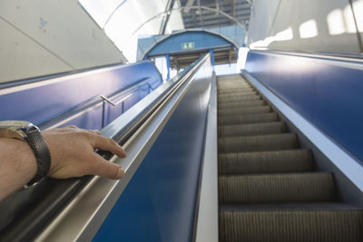 Cropped hand of man moving up on escalator