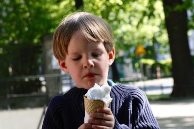 Boy holding ice cream cone on footpath