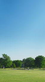 People playing soccer field against clear blue sky