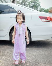 Cute girl standing against white car