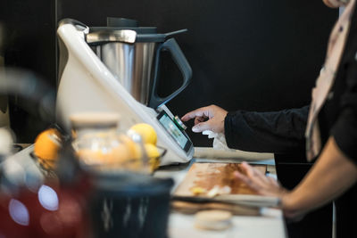 A lady attending to a cooking gadget in the kitchen