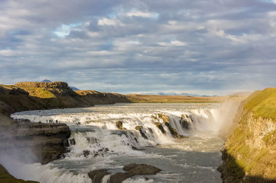 View of waterfall against cloudy sky