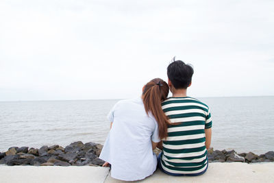 Rear view of couple on beach against sky