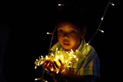 Close-up portrait of boy standing against black background