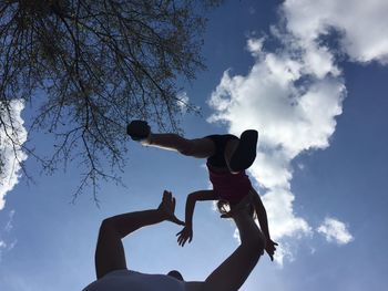 Low angle view of father playing with daughter against blue sky