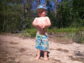 Full length of shirtless boy standing on land