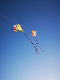 Low angle view of kite flying against clear blue sky