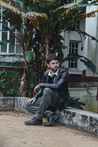 Full length of young man sitting outdoors