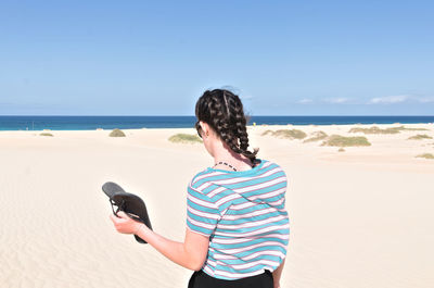 Rear view of man on beach against sky