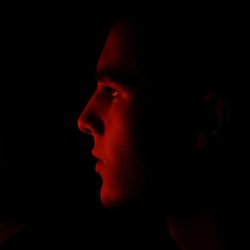 Close-up portrait of young man against black background