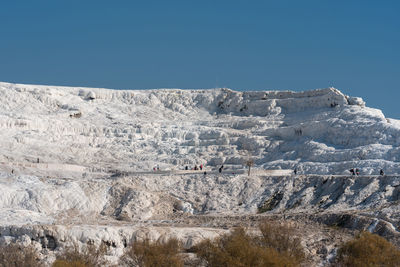 Scenic view of snowcapped mountains against clear blue sky