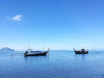 Boats sailing in sea against blue sky