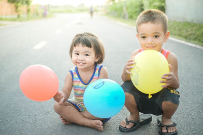 Siblings playing with balloons on road