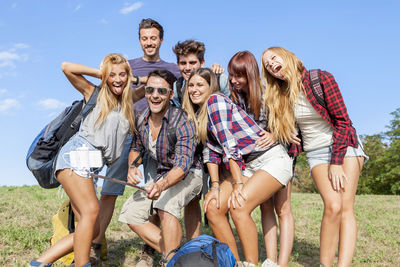 Portrait of smiling friends sitting on field