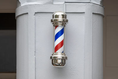 Close up of a barber pole signage on a grey wall