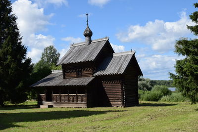 House amidst trees on field against sky