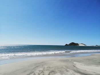 Scenic view of beach against clear blue sky