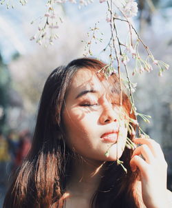 Close-up of young woman holding flower buds while standing at park