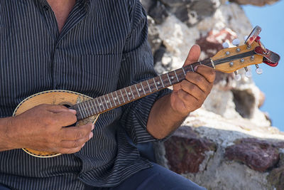 Midsection of man playing guitar