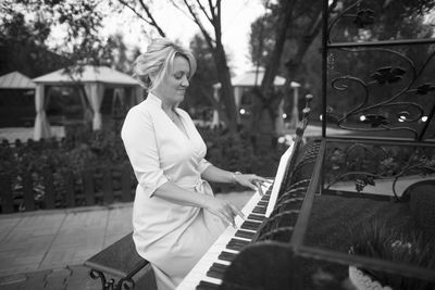 Woman playing piano while sitting outdoors