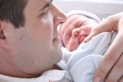 Close up portrait of father holding his sleeping newborn baby