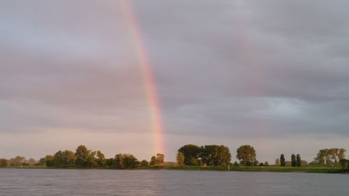 Scenic view of rainbow over lake against sky