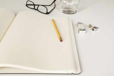 High angle view of school supplies with eyeglasses and drinking water over white background