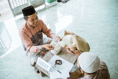 Happy young man donating rice at mosque