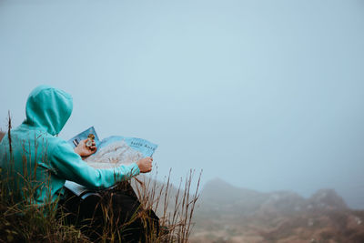 Man sitting on book against sky