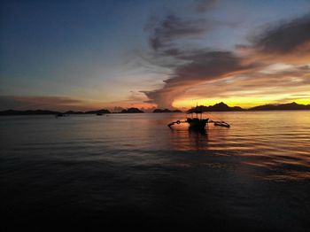 Silhouette boat in sea against sky during sunset