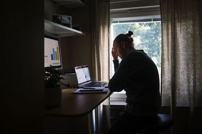 Silhouette of man using laptop at home