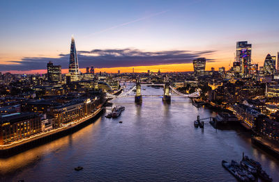 Illuminated buildings in city at sunset