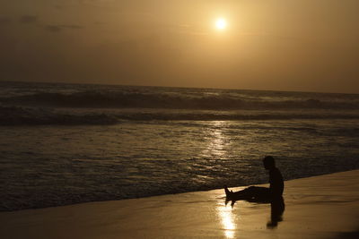 Silhouette people at beach against sky during sunset