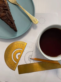 High angle view of coffee and cake on table with sketching tools