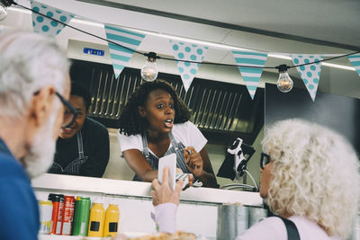 Female owner talking to customer about mobile payment while standing in food truck