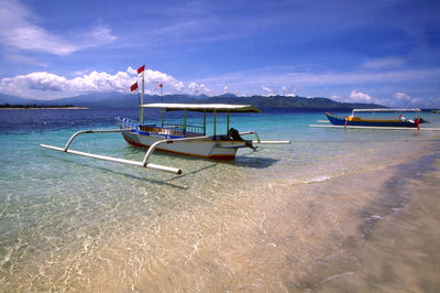 Outrigger boat at beach against sky