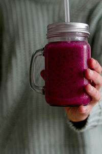 Person holding glass jug of delicious berry smoothie