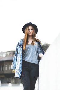 Portrait of young woman standing against clear sky