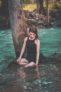 Portrait of a young woman sitting on tree trunk