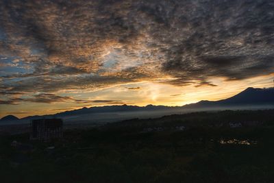 View of landscape against cloudy sky during sunset