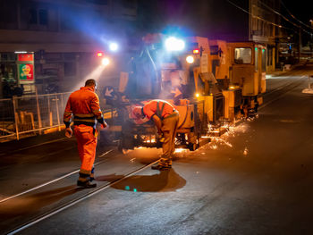 Rear view of people standing on road at night