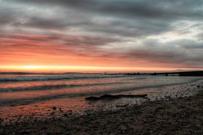 Scenic view of sea against dramatic sky during sunset