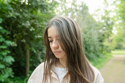 Young woman standing against trees